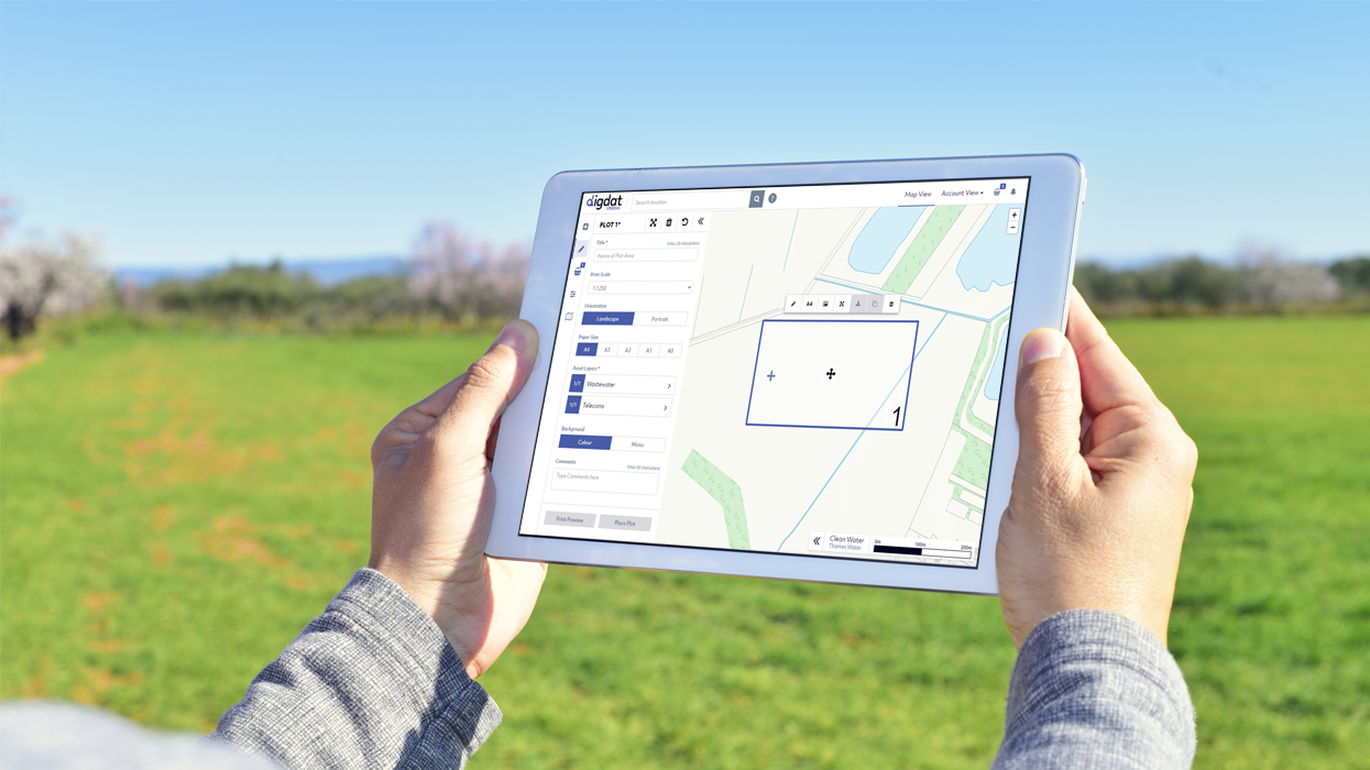 Person holding an ipad whilst stood in a field. They have digdat Utilities on the screen.